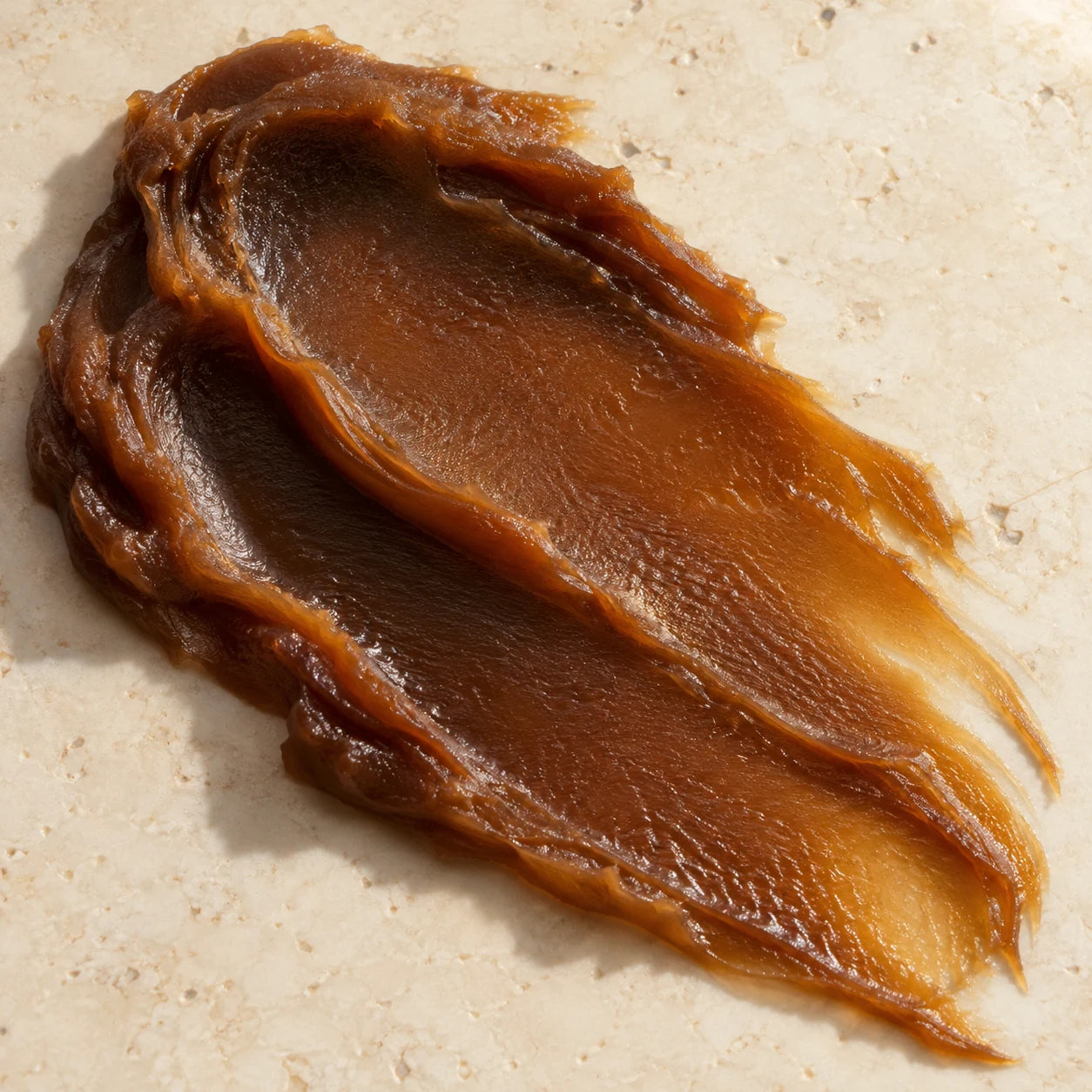 Rich unrefined brown cosmetic oil on warm stone
