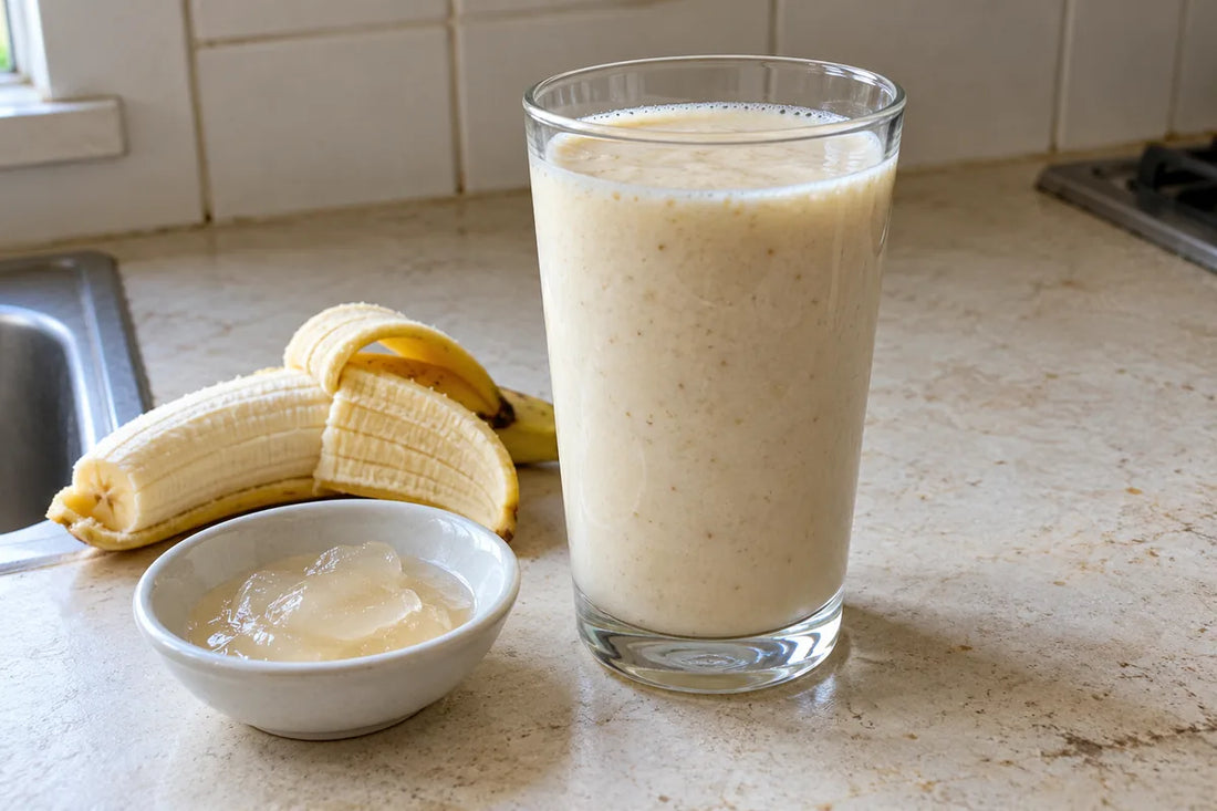 Banana smoothie in a clear glass beside a banana and a small dish of sea moss gel