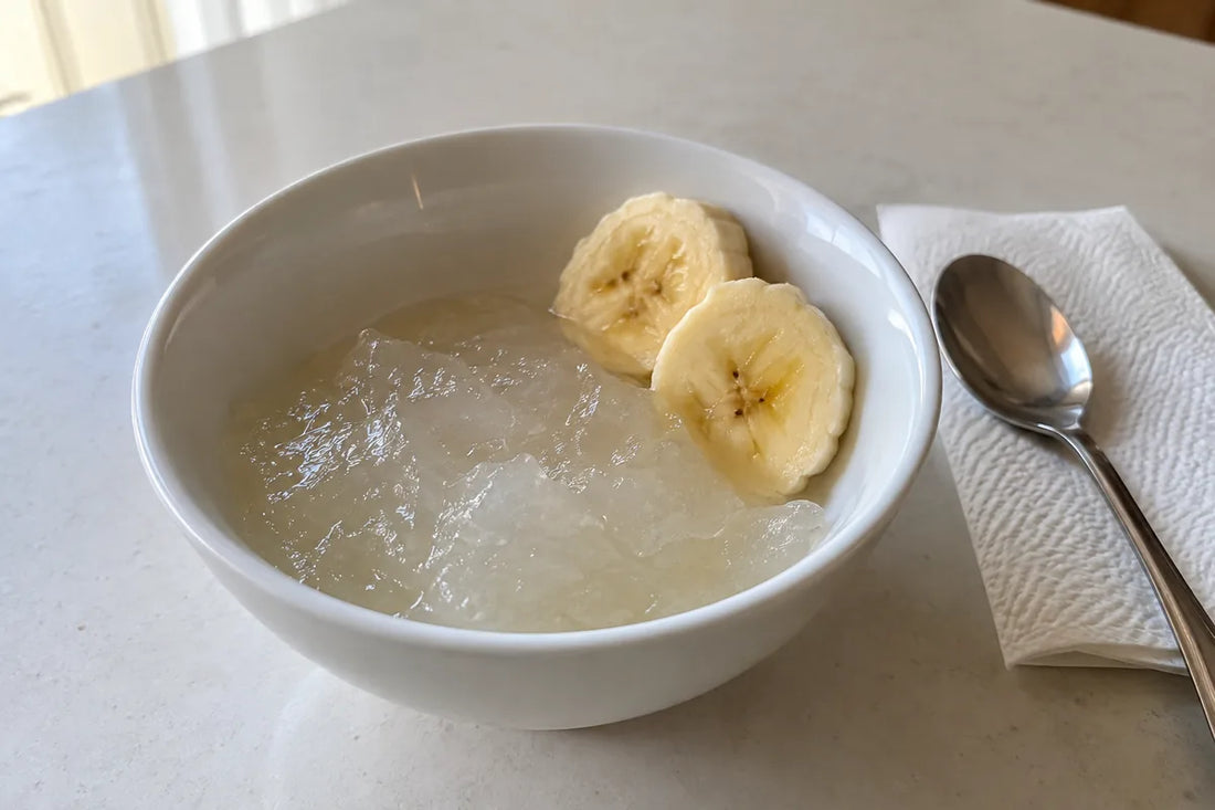 Pale sea moss gel in a small bowl beside banana slices and a teaspoon